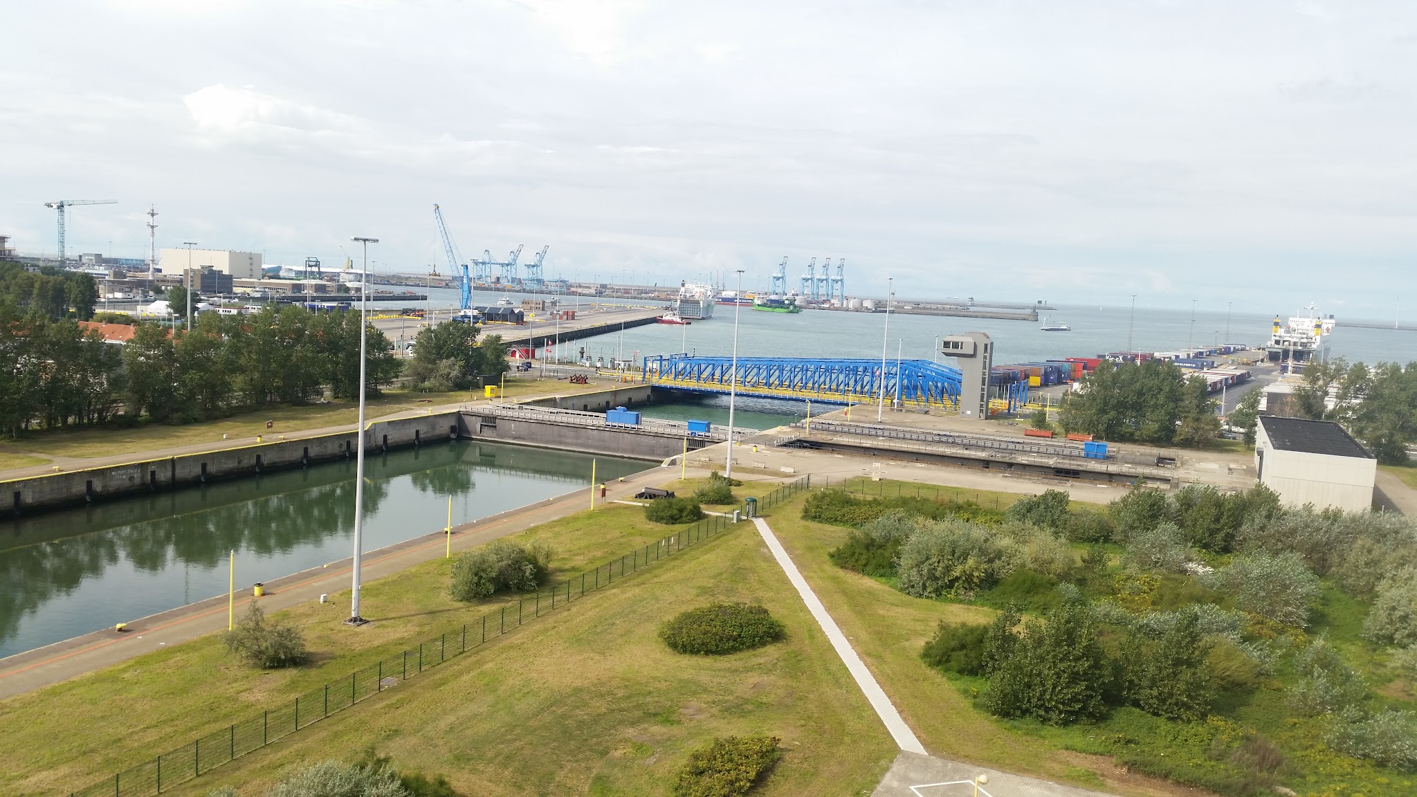 Blick auf Hafen mit Schleuse, blauem Brückentor, Containerkränen und Fähre am Kai