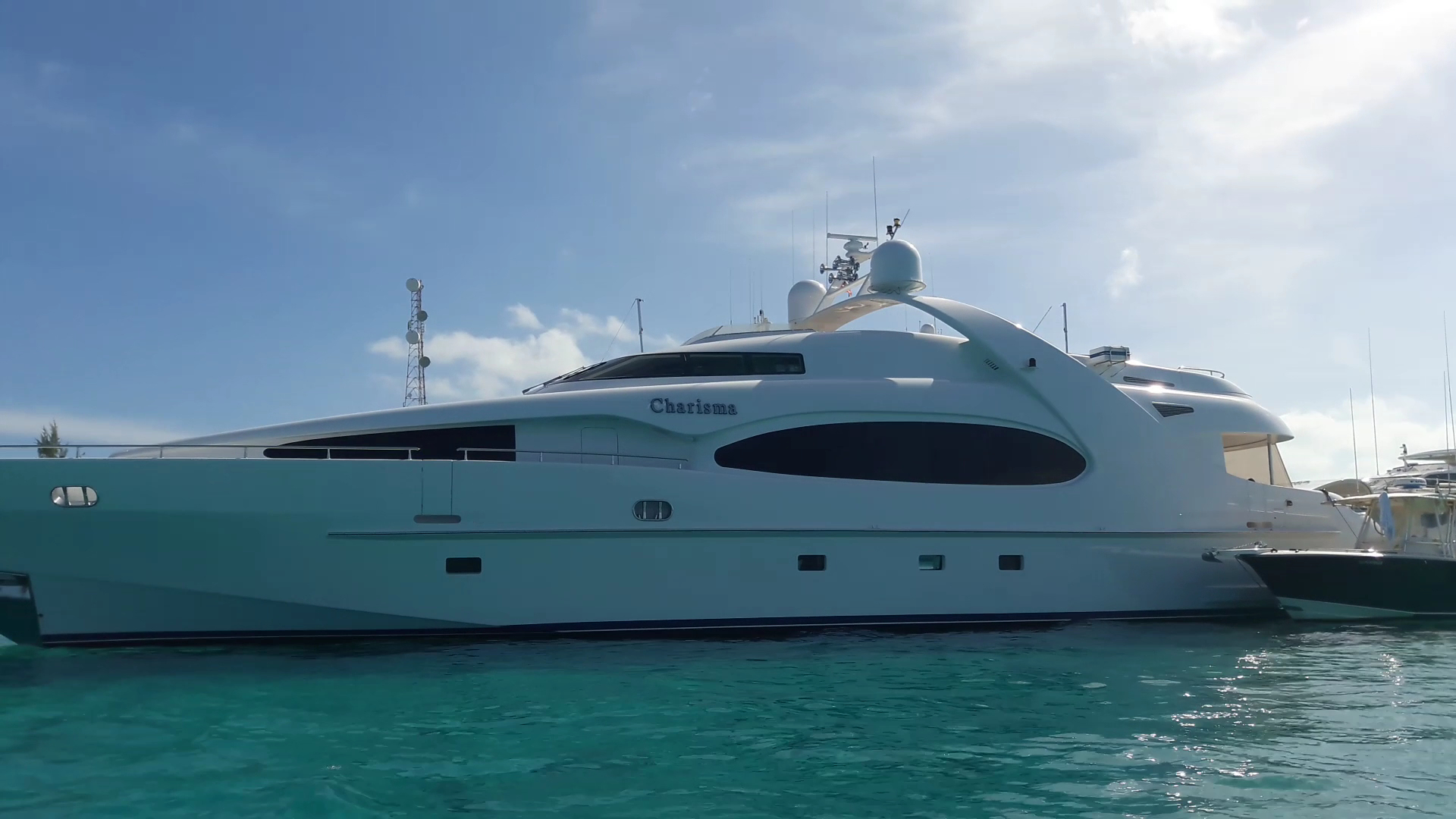 Weiße Luxusyacht „Charisma“ liegt seitlich im türkisgrünen Wasser unter blauem Himmel.