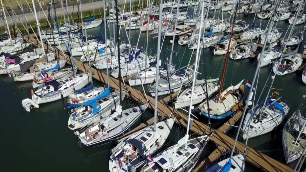 Vogelperspektive: Dicht aneinandergereihte Segelboote an Holzstegen in einem vollen Jachthafen