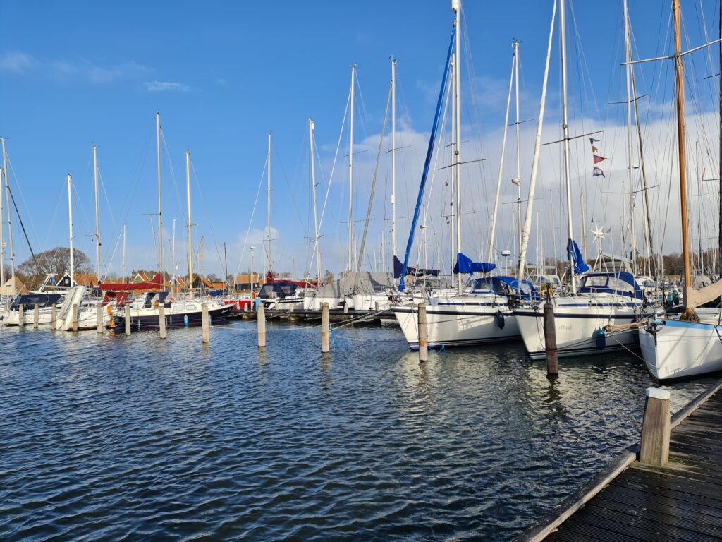 Yachthafen mit dicht aneinander liegenden Segelbooten, vielen Masten vor blauem Himmel, ruhiges Wasser