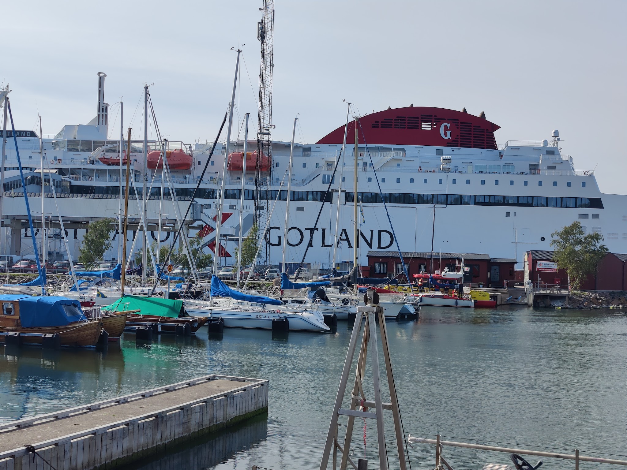 Große Gotland-Fähre im Hafen, davor zahlreiche Segelboote mit hochragenden Masten.