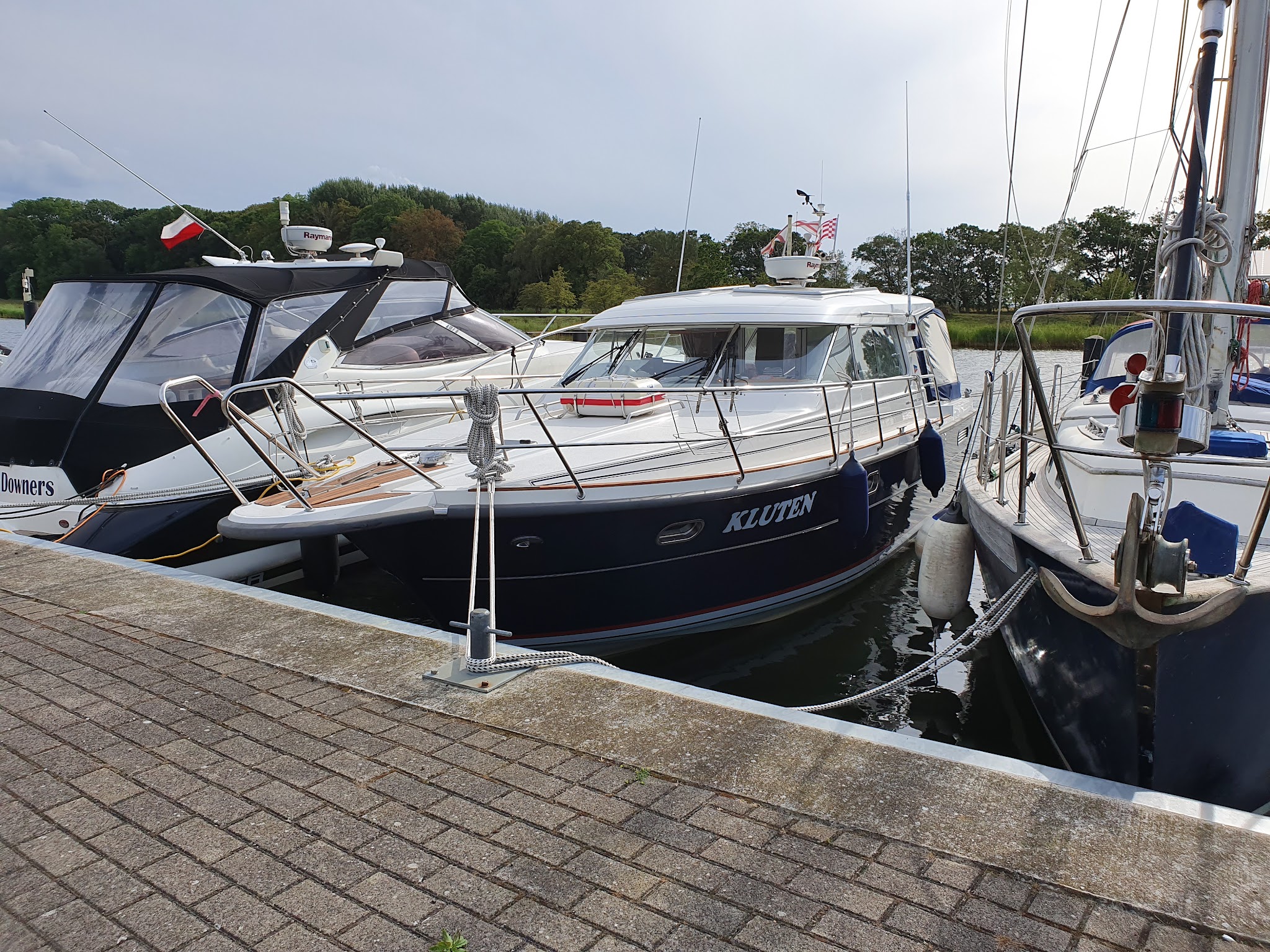 Drei Motor- und Segelyachten liegen eng nebeneinander am Steg, Hauptboot „KLUTEN“ vorne, Wasser ruhig.