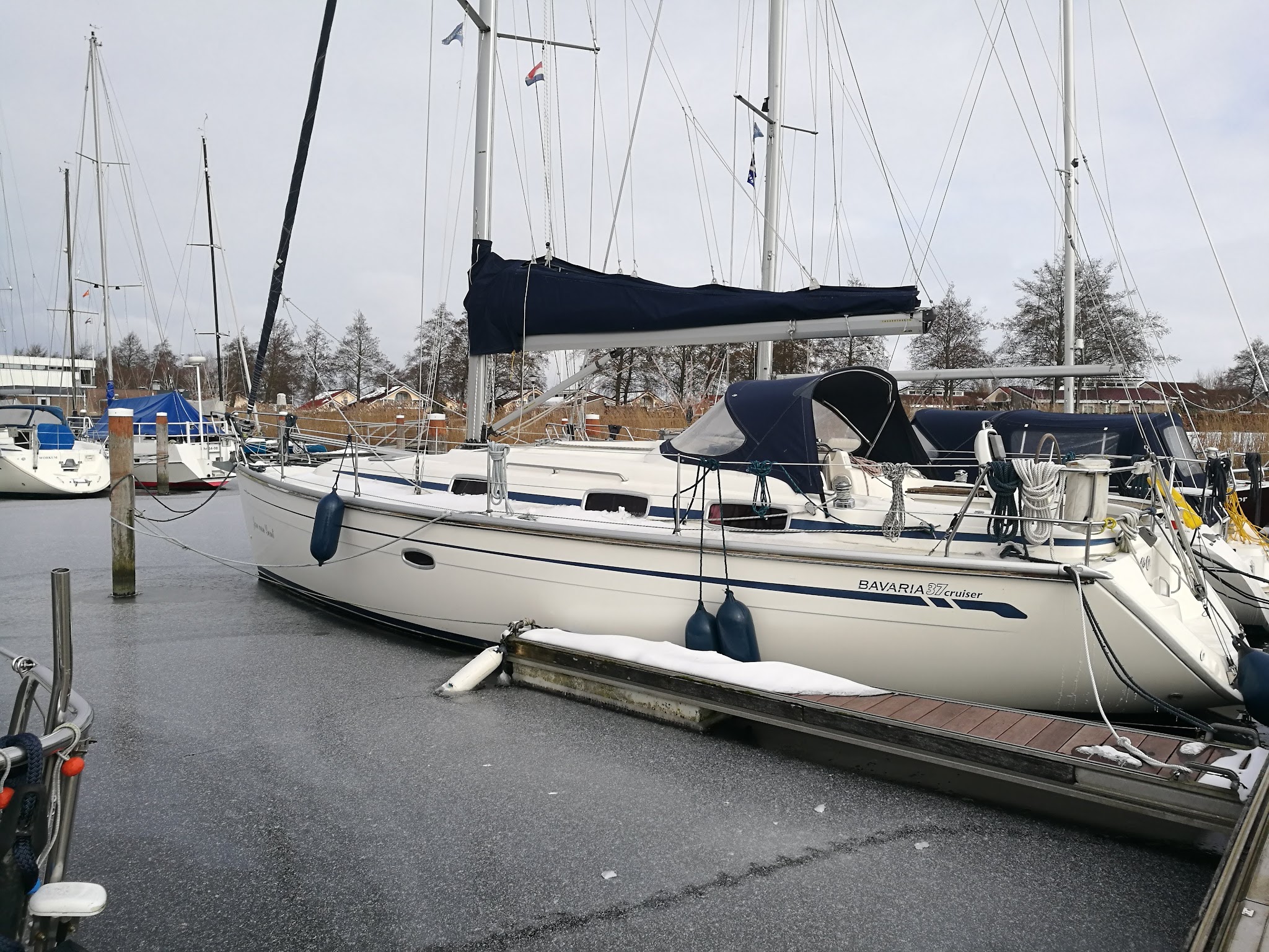 Festgemachte Segelyacht in vereistem Hafen, Schnee auf Steg, ruhige Winterstimmung
