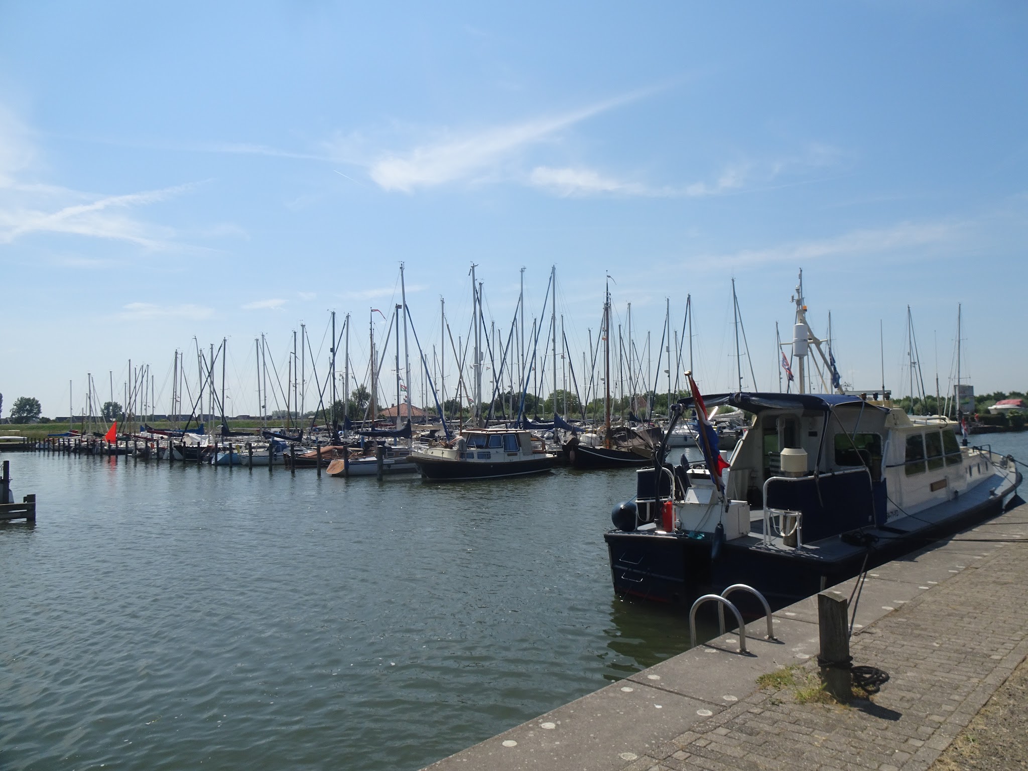 Yachthafen mit zahlreichen Segelbooten unter blauem Himmel, vorn ein festgemachtes Motorboot am Kai