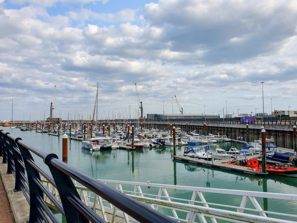 Bootshafen mit dicht aneinandergereihten Segel- und Motorbooten, Blick über Geländer auf ruhiges Wasser